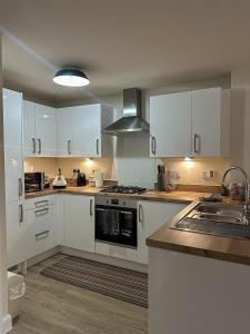 a kitchen with white cabinets and a stove top oven at The Calm Space Room in Balderton