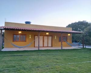 a small yellow house with a large yard at Casa Refúgio do Rio in Caraíva