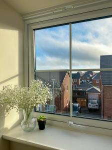 a window with a vase and flowers on a counter at The Calm Space Room in Balderton