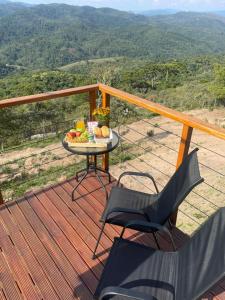 a table with a plate of fruit on a deck at Chalé Colinas in Campos do Jordão