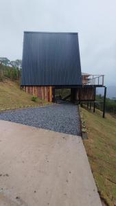 a building with a black roof on top of a field at Chalé Colinas in Campos do Jordão