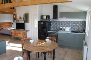 a kitchen with a table and a kitchen with a black refrigerator at L'Effet Mer - Côte D'Albâtre in Saint-Martin-Plage