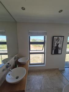 een badkamer met 2 wastafels en een raam bij Beach House in Pearly Beach