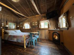een slaapkamer met een bed, een tafel en een open haard bij The Renovated Barn at Seneca Rocks in Seneca Rocks