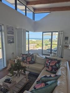 een woonkamer met een witte bank en een groot raam bij Beach House in Pearly Beach