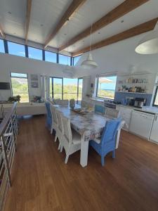 een grote keuken met een tafel, stoelen en ramen bij Beach House in Pearly Beach