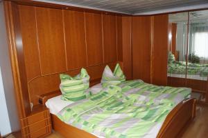 a bed with green and white sheets and pillows at Ferienhaus Am Arzberg in Kurort Steinbach-Hallenberg +6 photos