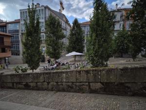 a stone wall with trees and tables in front of a building at Escola in Ourense