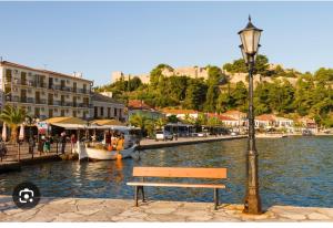 een bankje en een straatlantaarn naast een rivier met een boot bij Prodromiti's House in Vonitsa