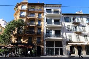 ein hohes weißes Gebäude mit Balkonen an einer Straße in der Unterkunft Nümad Suites in Nizza