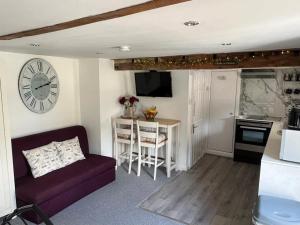 a living room with a couch and a clock on the wall at Pitfield Apartments in Willand