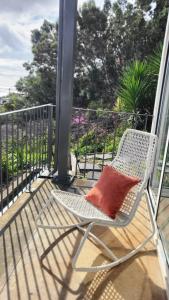 a white chair with a red pillow on a porch at Personal blue house Madeira in Santa Cruz