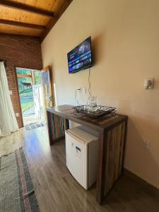 a room with a counter with a television on the wall at Pousada Casa do Geninho in Conceição da Ibitipoca
