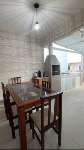 a kitchen with a wooden table with chairs and a stove at Casa Premium com Jacuzzi e Churrasqueira in Palhoça