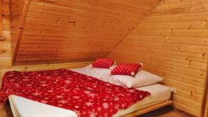 un letto in una sauna con lenzuola e cuscini rossi di Chata nad Roztokami a Baligród