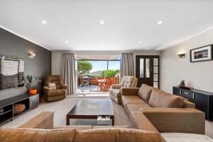 a living room with a couch and a table at Silver Seas Retreat in Muriwai Beach