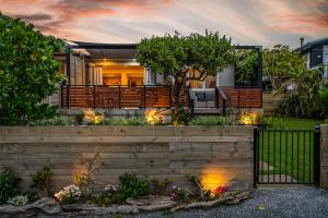a home with a wooden fence and a garden at Silver Seas Retreat in Muriwai Beach