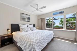 a bedroom with a bed and two windows at Silver Seas Retreat in Muriwai Beach
