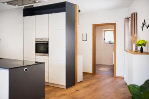 una cucina con mobili bianchi e un piano di lavoro nero di ALTE MÜHLE LOFT - AlpenLuxus Collection a Brixlegg