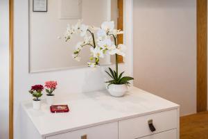 un mobile bianco con due vasi di fiori sopra di ALTE MÜHLE LOFT - AlpenLuxus Collection a Brixlegg