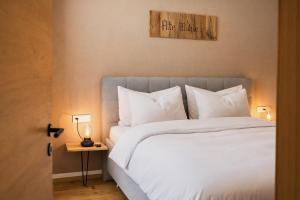 una camera da letto con un letto con lenzuola e cuscini bianchi di ALTE MÜHLE LOFT - AlpenLuxus Collection a Brixlegg Altre 20 foto