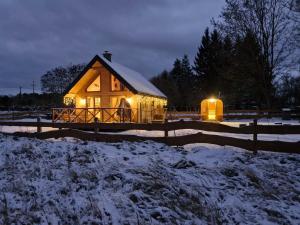 a lit up cabin in the snow at night at Hygge z kominkiem i sauna Piasek Cedynia Chojna in Piasek