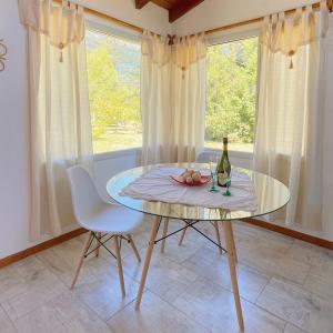 a glass table with a bottle of wine and two chairs at Los Nenúfares in Lago Puelo