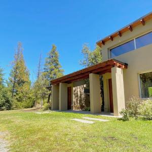 a house with a green lawn in front of it at Los Nenúfares in Lago Puelo