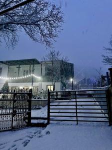 a fence covered in snow in front of a building at View Racha in Ambrolauri