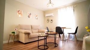 un soggiorno con un divano, un tavolo e delle sedie di Suites Cañizares Catedral a Jaén