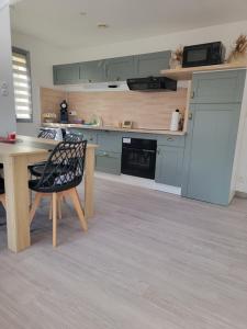 a kitchen with green cabinets and a table and a chair at Maison Cocooning Equihen 5 pers Proche Mer & Terrasse in Équihen-Plage