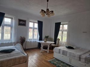 una camera da letto con due letti, un tavolo e finestre di La Cetate Transilvania a Moşna