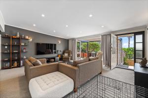 a living room with a couch and a tv at Silver Seas Retreat in Muriwai Beach +12 photos
