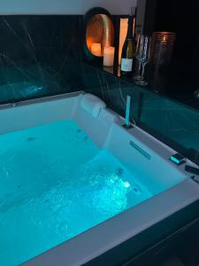 a bath tub with blue water in a bathroom at L'alcôve Clisson-Love room- Gîte Romantique-SPA in Clisson