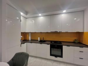 a kitchen with white cabinets and a stove top oven at Nivora apartament #freeparking in Tunari