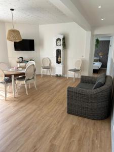 a living room with a couch and a table and chairs at Gite MIRABELLE in Saint-Rémy-Boscrocourt
