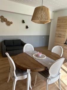 a dining room table with white chairs and a couch at Gite MIRABELLE in Saint-Rémy-Boscrocourt