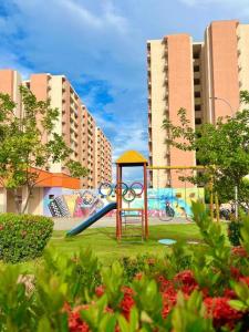 un parco giochi con scivolo in un parco con edifici di Acogedor y elegante Apartamento a Valledupar