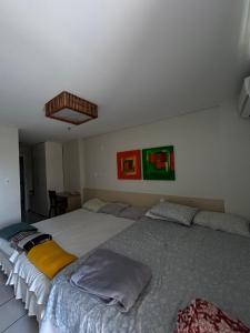 a bedroom with two large beds and paintings on the wall at Condomínio Lençóis Flat Resdence in Barreirinhas +7 photos