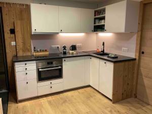 a kitchen with white cabinets and a black counter top at Superbe terrasse proximité centre in Morzine
