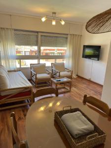 a living room with chairs and a table and a tv at Edificio Carbe Punta del Este - Frente al Mar -parada 2 de la Mansa in Punta del Este