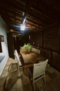 a dining room with a wooden table and white chairs at Casa do Prãna in Guajiru