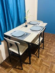 a wooden table with four chairs and blue plates at Departamento Flores in Catemaco