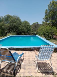 twee stoelen naast een zwembad bij La Pasionaria, casa de campo con pileta in Villa García