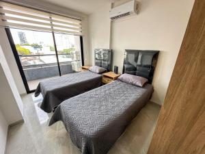 two beds in a room with a window at Dulce Experiencia Departamento de 2 dormitorios in Santa Cruz de la Sierra +12 photos