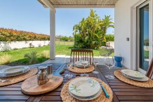 a wooden table with plates and wine glasses on a patio at Villa Leomaris in Torre dell'Orso
