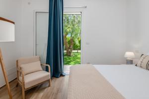 a bedroom with a bed and a chair and a window at Villa Leomaris in Torre dell'Orso