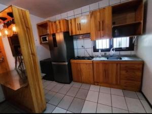 a kitchen with wooden cabinets and a black refrigerator at POUSADA TEMPORADA BIBi casa inteira com café in São Gabriel