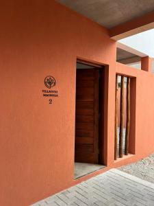 a orange building with a door and a sign on it at Vilaggio Magnolia in Cafayate +8 photos
