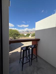 two bar stools sitting at a counter on a balcony at Vilaggio Magnolia in Cafayate